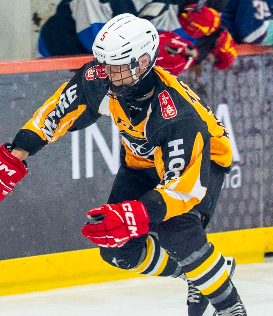 Torres Leung carrying the puck in a Hong Kong jersey