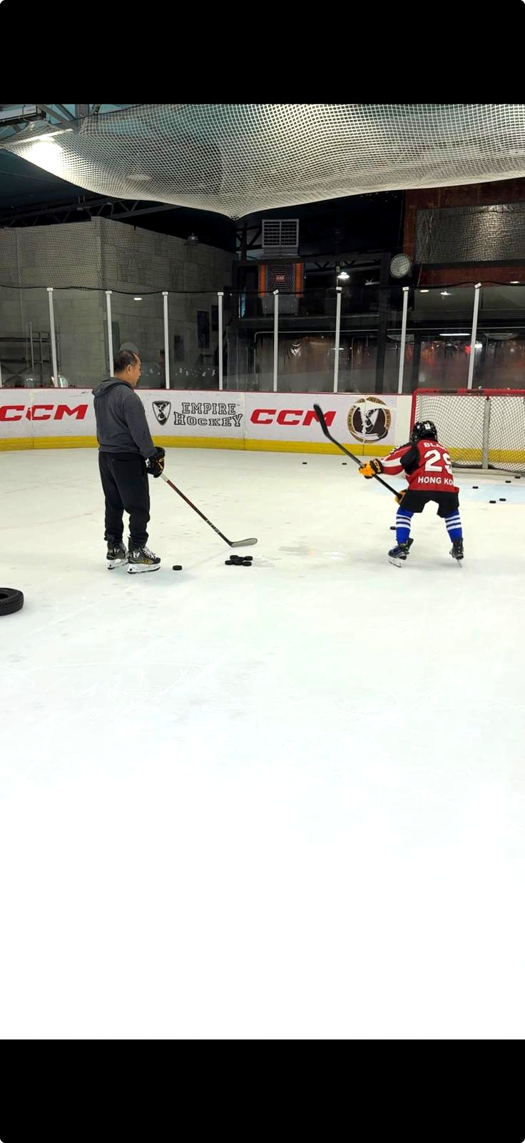 A young player taking shots with a coach at Empire Rink